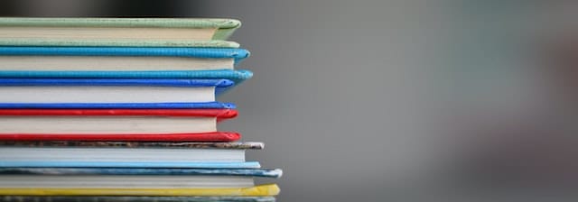 a pile of books with covers in different colours in front of a grey, blurred background